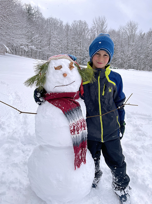 Student next to a snowman outside