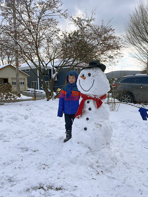 Student posing next to a snowman outside